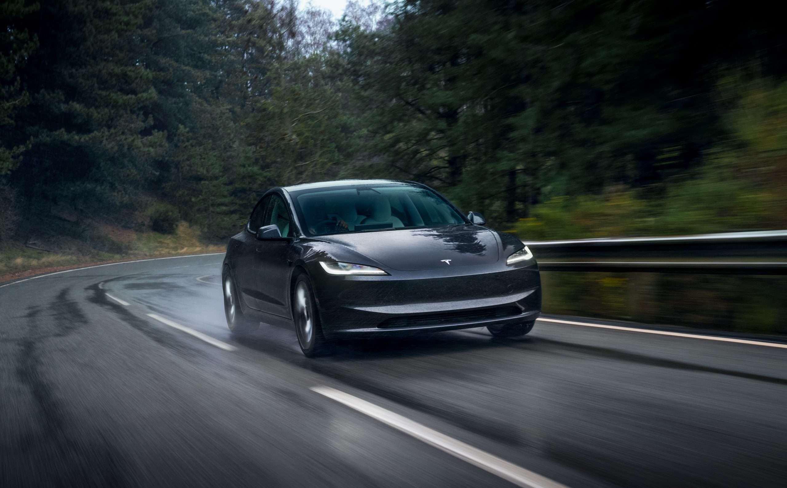 tesla model 3 driving on a wet road